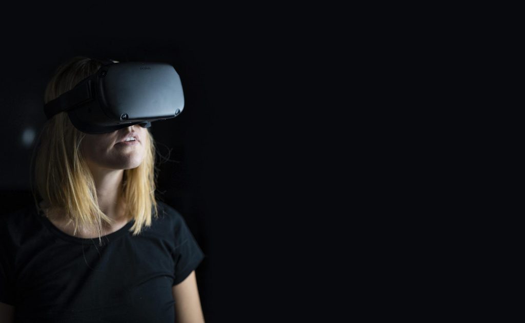 Une femme qui porte un casque virtuel pendant un team building en réalité virtuelle.