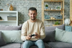 Joueur de jeu vidéo installé sur un canapé, avec une manette de Playstation